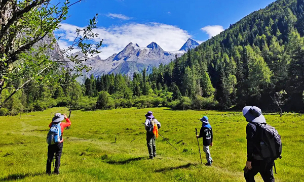 Hikers trekking through alpine meadows in Mount Siguniang