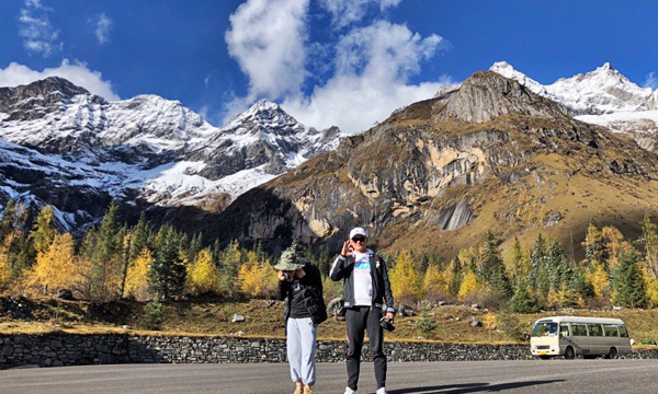 Travelers arriving at Mount Siguniang with snow-capped mountains in the background
