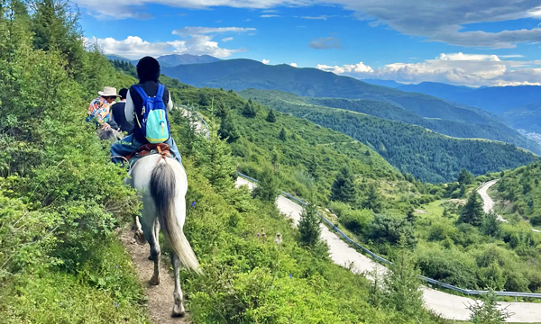 traveler riding a horse through the mountains around Songpan