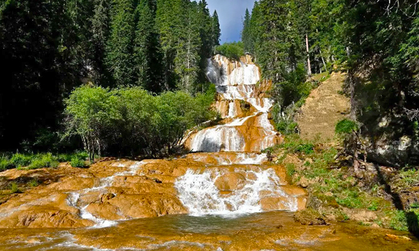 multi-level Zhaga Waterfall surrounded by forest in Munigou Valley