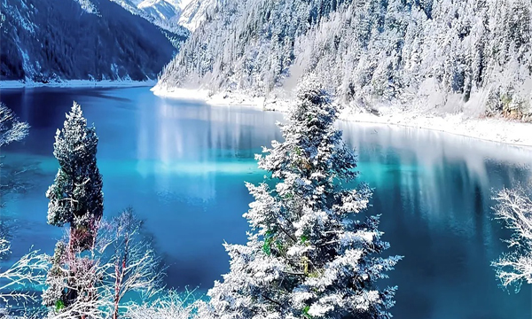 Jiuzhaigou winter scenery with snow-covered forests and blue lake