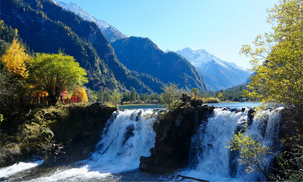 Bipeng Valley waterfall with forests and snow mountains in Sichuan